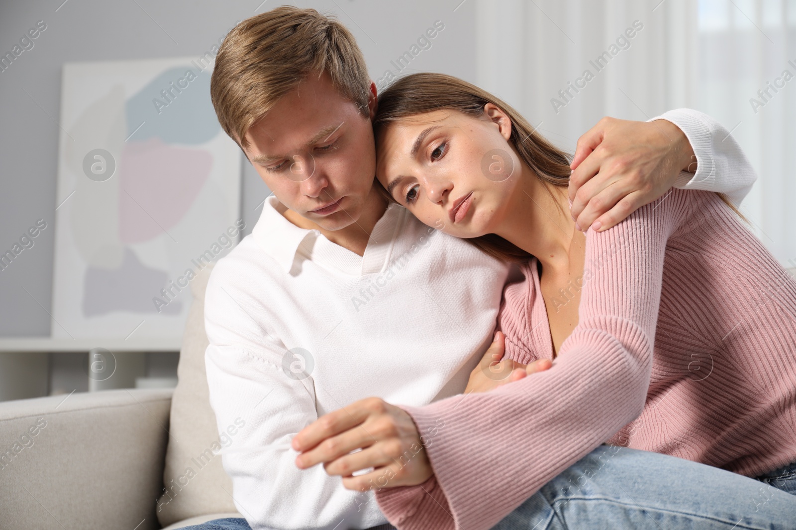 Worried couple with pregnancy test on sofa at home Photo of Worried couple with pregnancy test on sofa at home