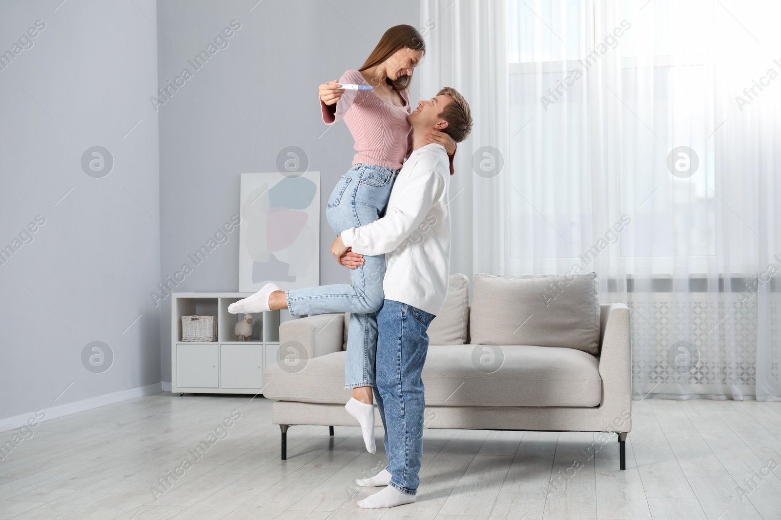 Photo of Happy couple with pregnancy test at home