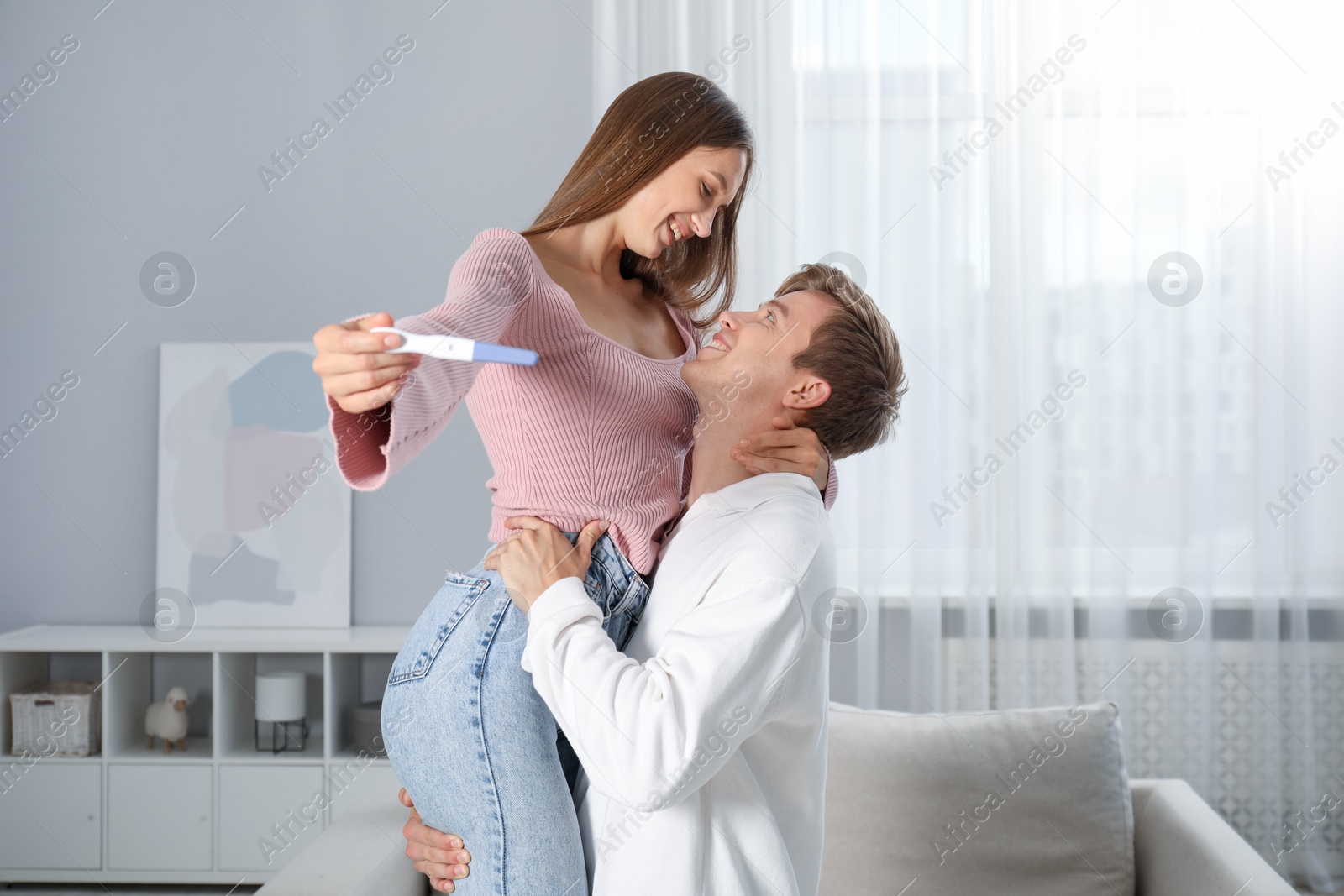 Photo of Happy couple with pregnancy test at home