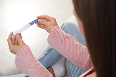 Photo of Woman with positive pregnancy test indoors, closeup