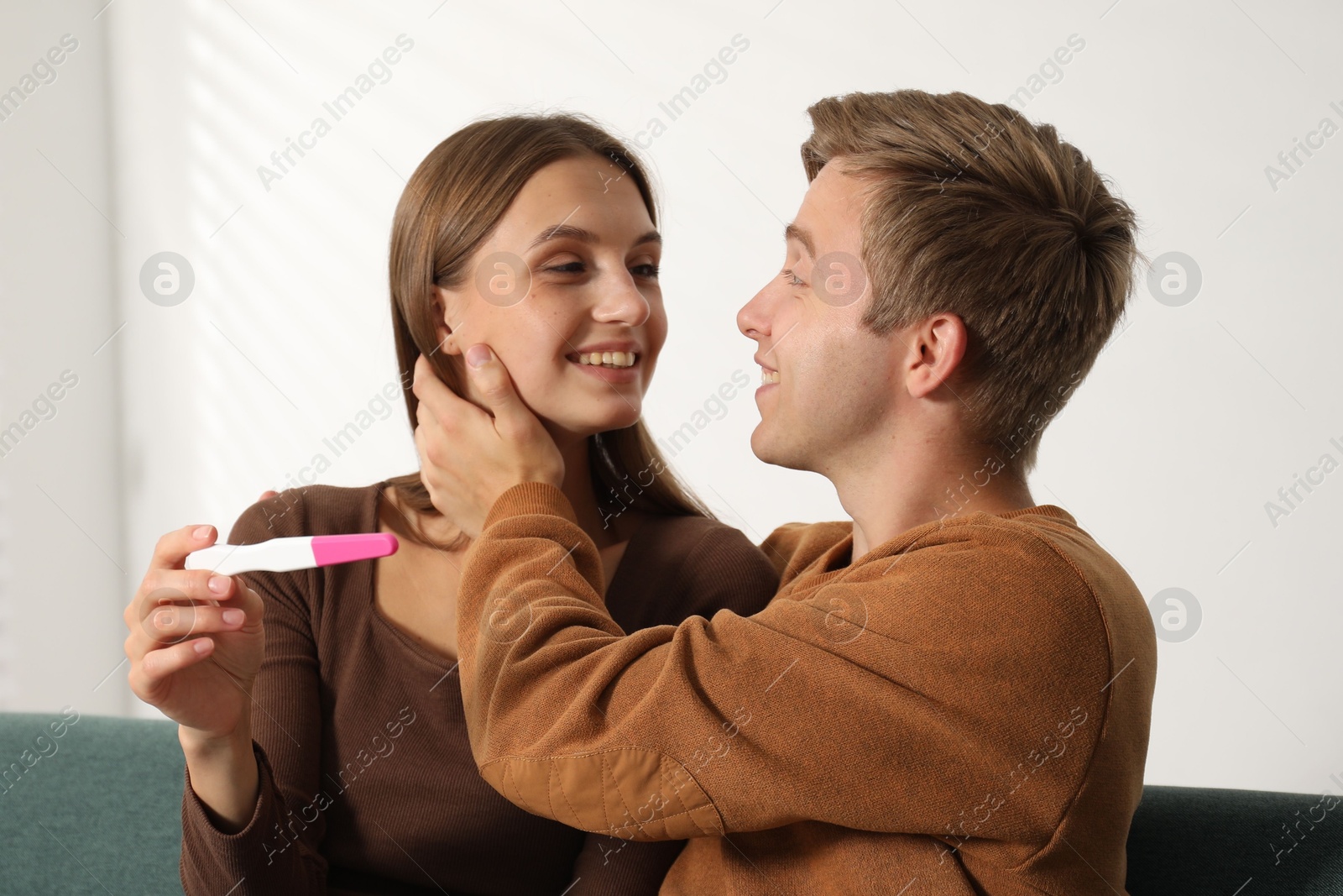 Photo of Happy couple with pregnancy test at home