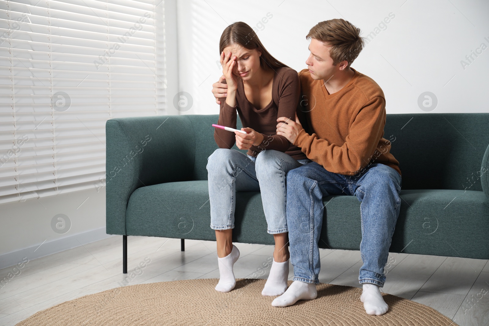 Worried couple with pregnancy test on sofa at home Photo of Worried couple with pregnancy test on sofa at home