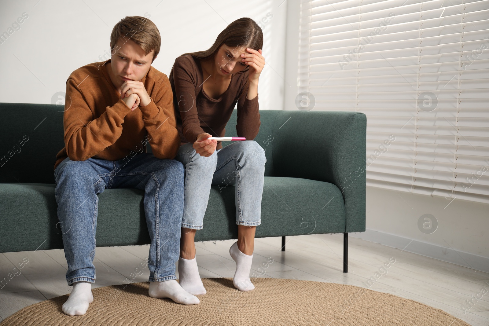 Worried couple with pregnancy test on sofa at home Photo of Worried couple with pregnancy test on sofa at home