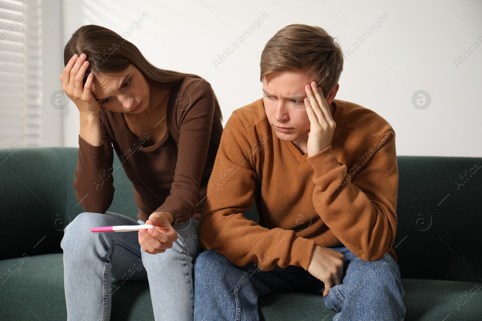Worried couple with pregnancy test on sofa at home Photo of Worried couple with pregnancy test on sofa at home