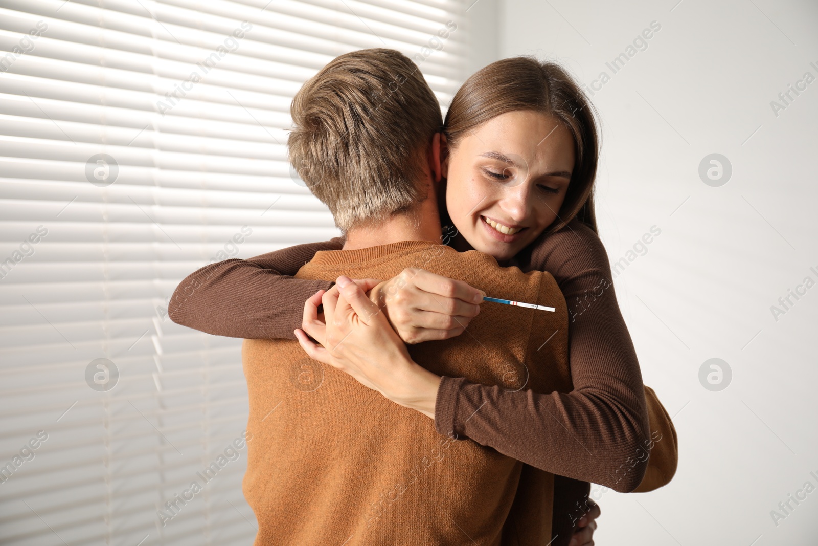 Photo of Happy couple with pregnancy test at home