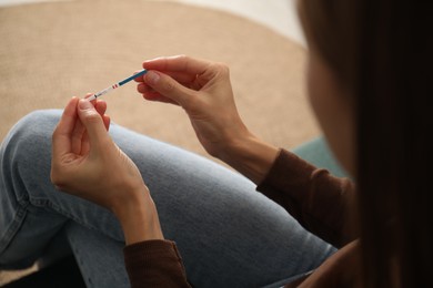 Photo of Woman with positive pregnancy test indoors, closeup