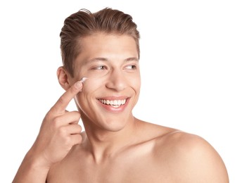 Photo of Handsome young man applying cream onto his face on white background
