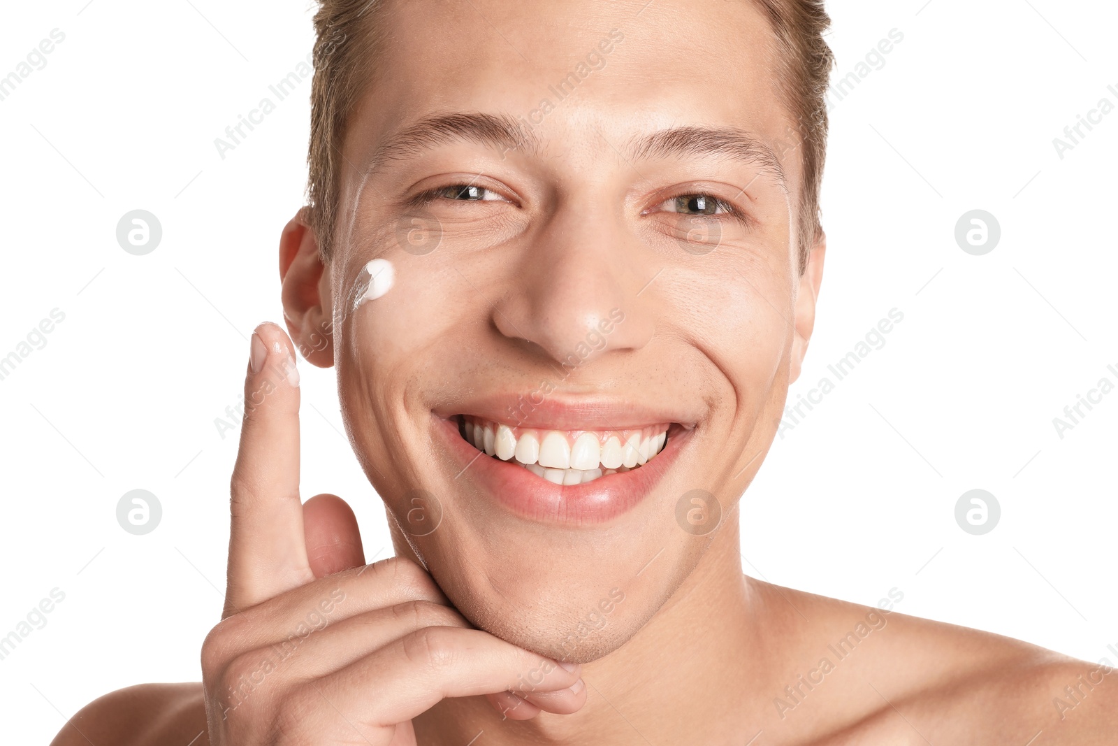 Photo of Handsome young man applying cream onto his face on white background, closeup