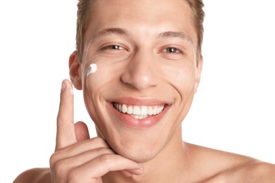Photo of Handsome young man applying cream onto his face on white background, closeup