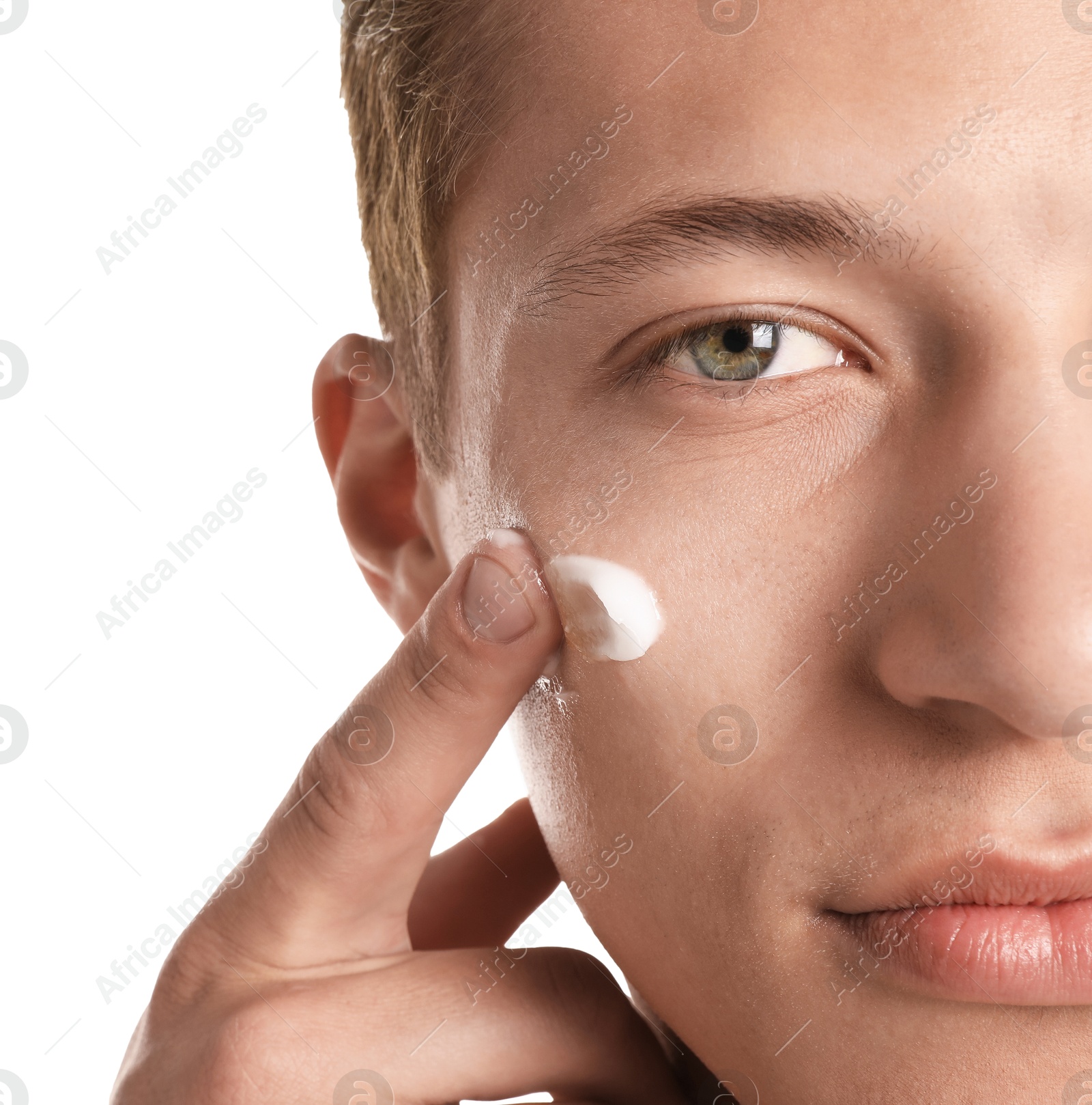 Photo of Handsome young man applying cream onto his face on white background, closeup