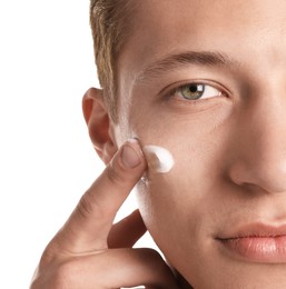 Photo of Handsome young man applying cream onto his face on white background, closeup