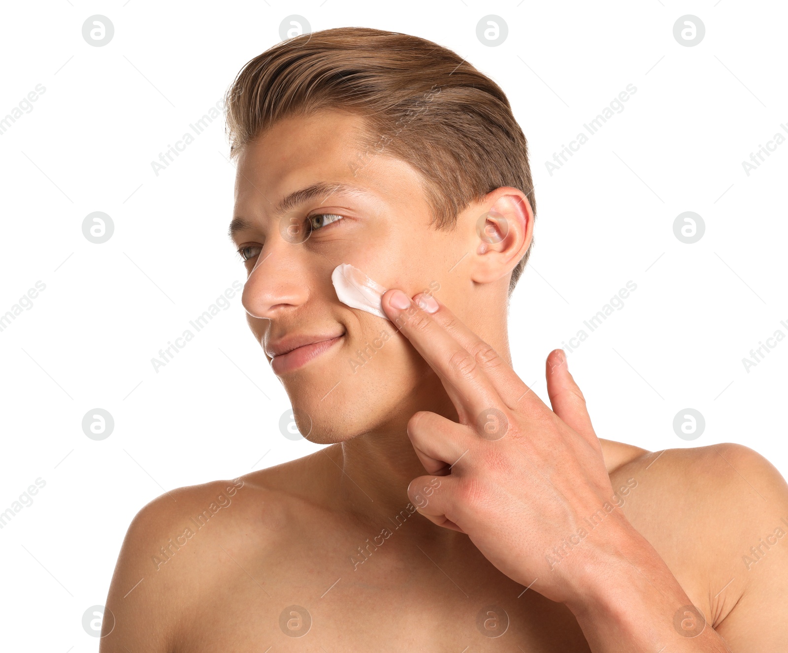 Photo of Handsome young man applying cream onto his face on white background