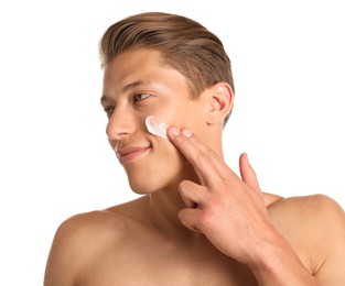 Photo of Handsome young man applying cream onto his face on white background