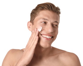Photo of Handsome young man applying cream onto his face on white background
