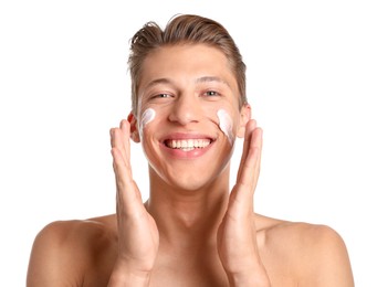 Photo of Handsome young man applying cream onto his face on white background