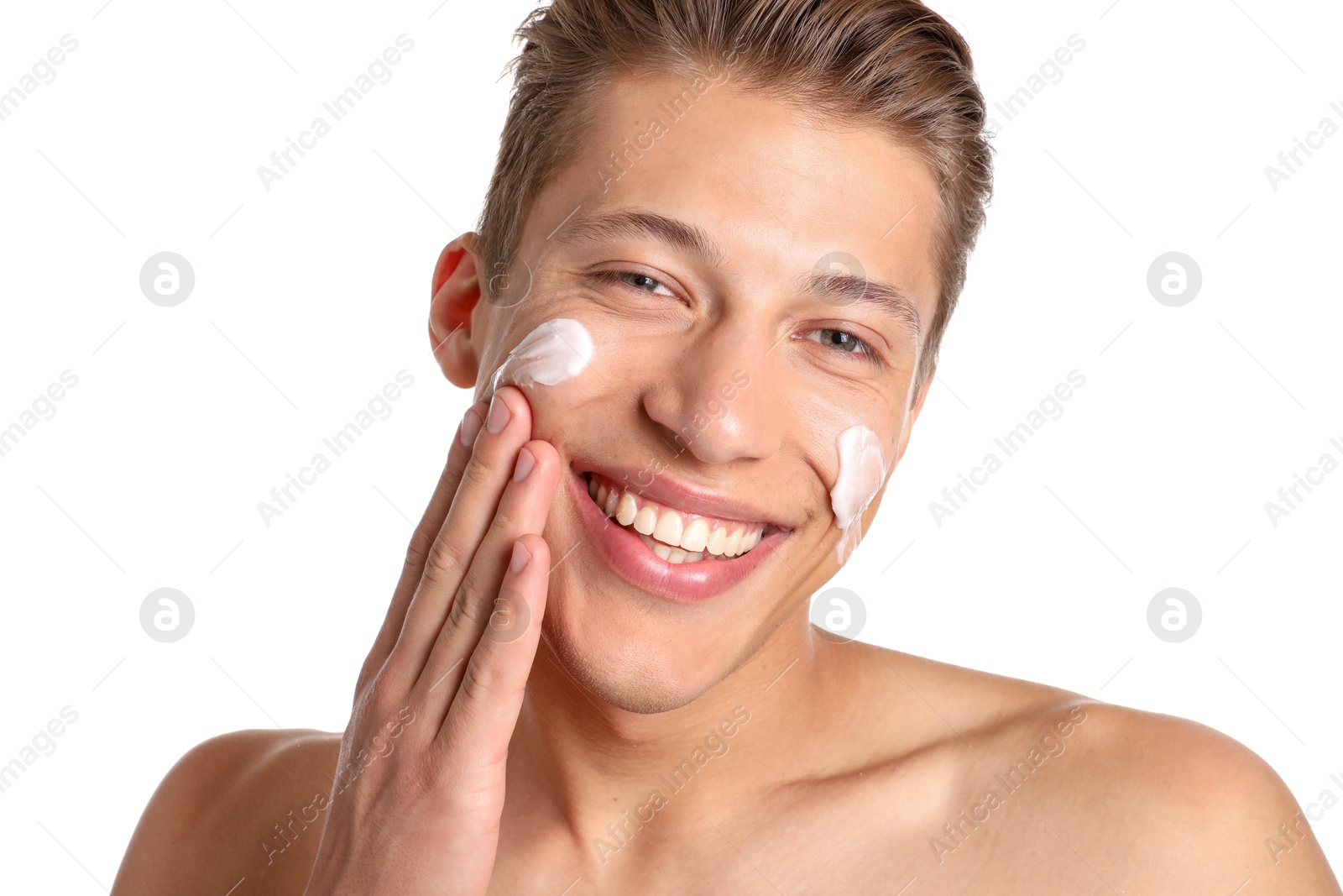 Photo of Handsome young man applying cream onto his face on white background, closeup
