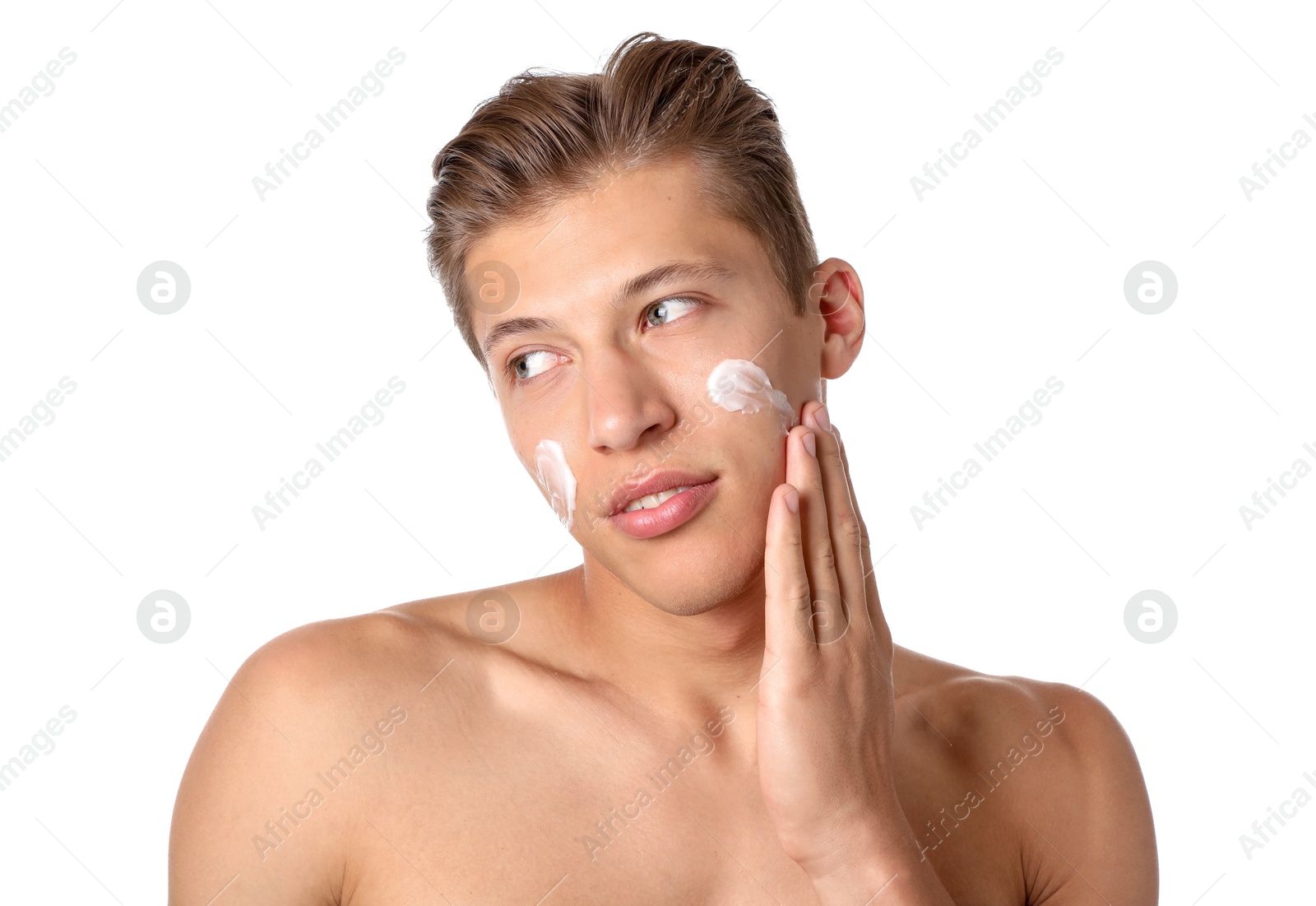 Photo of Handsome young man applying cream onto his face on white background