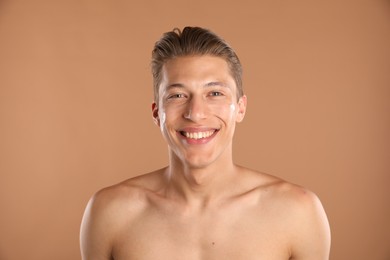 Photo of Handsome young man with cream on his face against light brown background