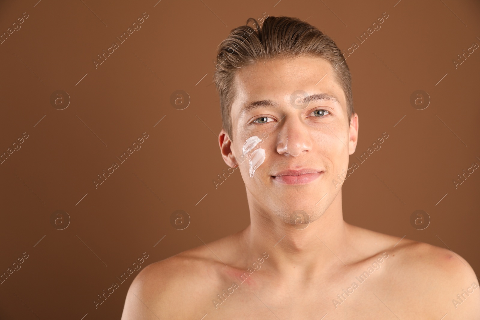 Photo of Handsome young man with cream on his face against brown background, space for text