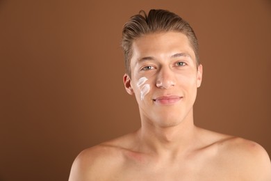 Photo of Handsome young man with cream on his face against brown background, space for text