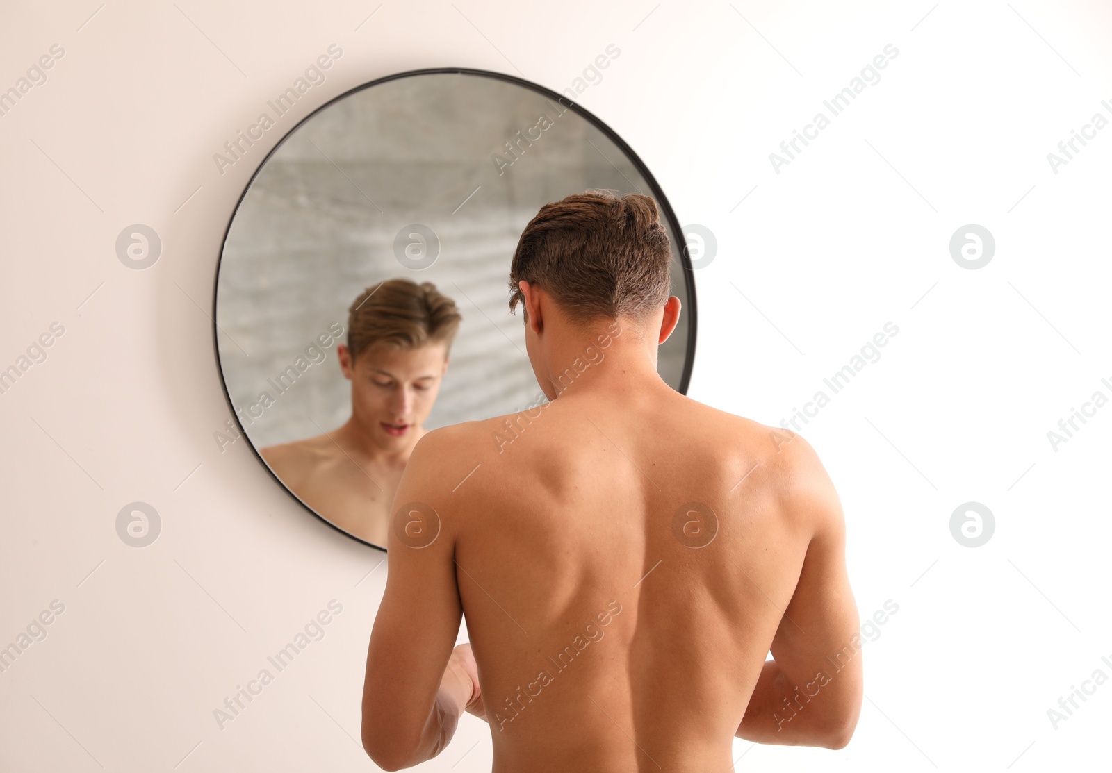 Photo of Handsome young man near mirror at home, selective focus