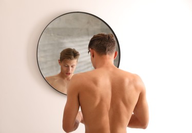 Photo of Handsome young man near mirror at home, selective focus