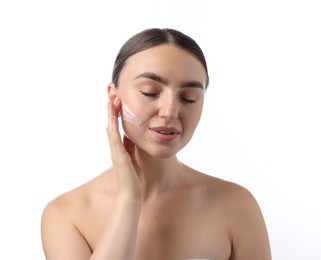 Photo of Beautiful woman applying cream onto her face on white background