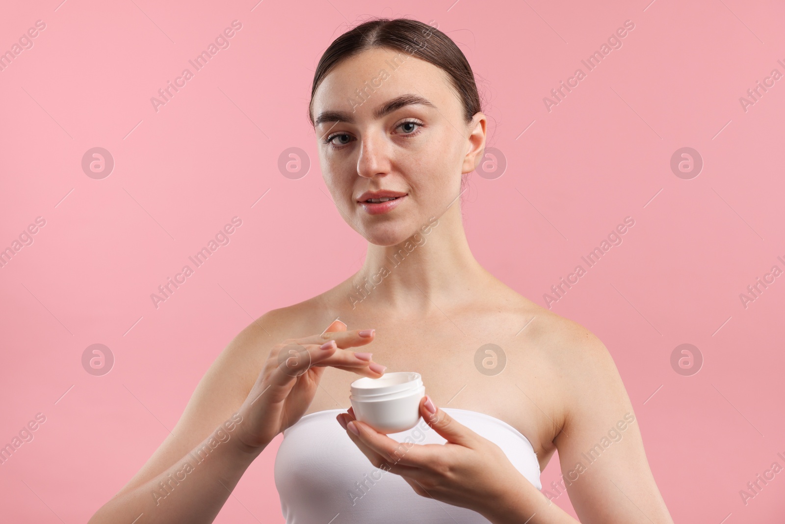 Photo of Beautiful woman with jar of face cream on pink background
