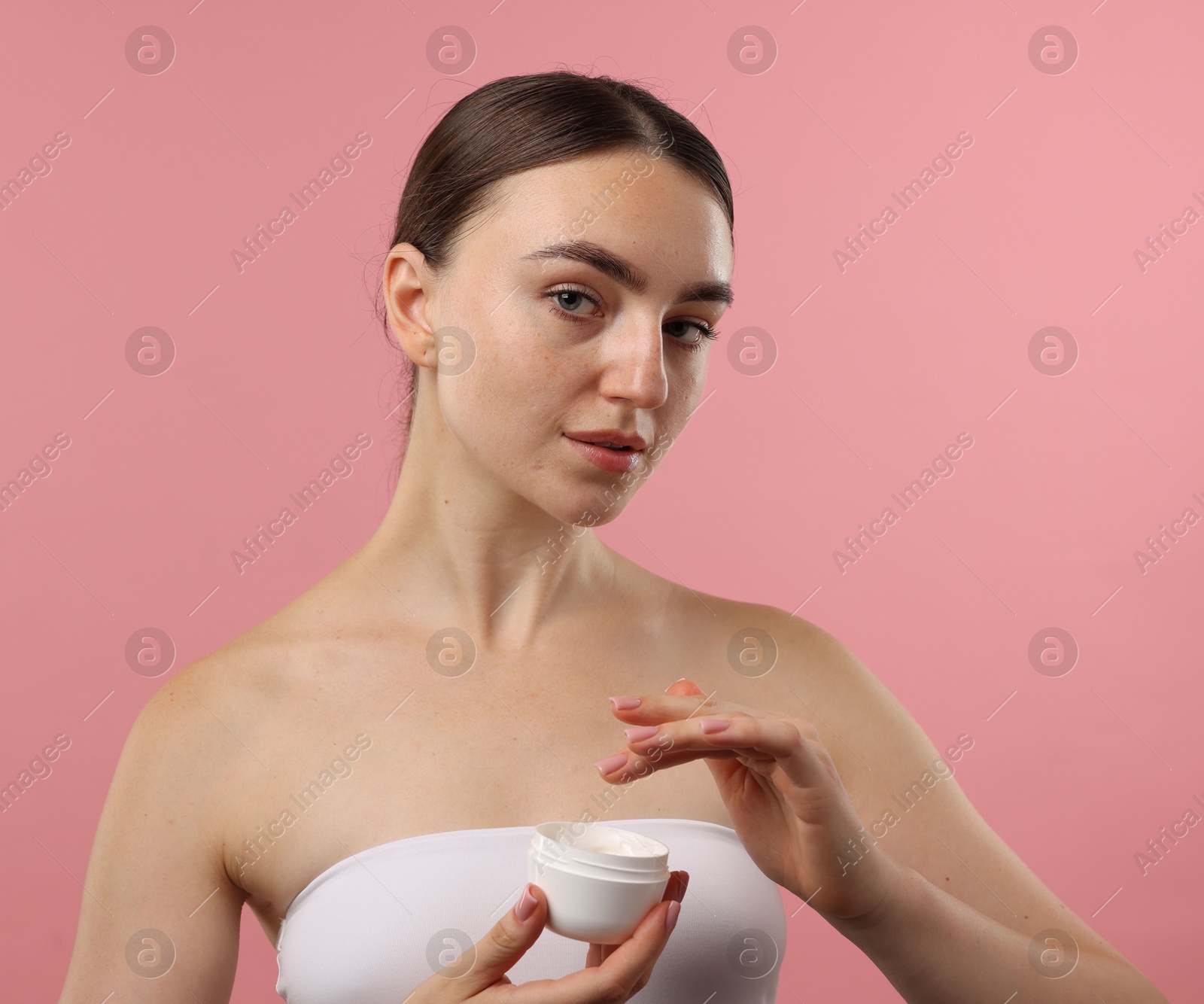 Photo of Beautiful woman with jar of face cream on pink background