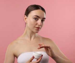 Photo of Beautiful woman with jar of face cream on pink background