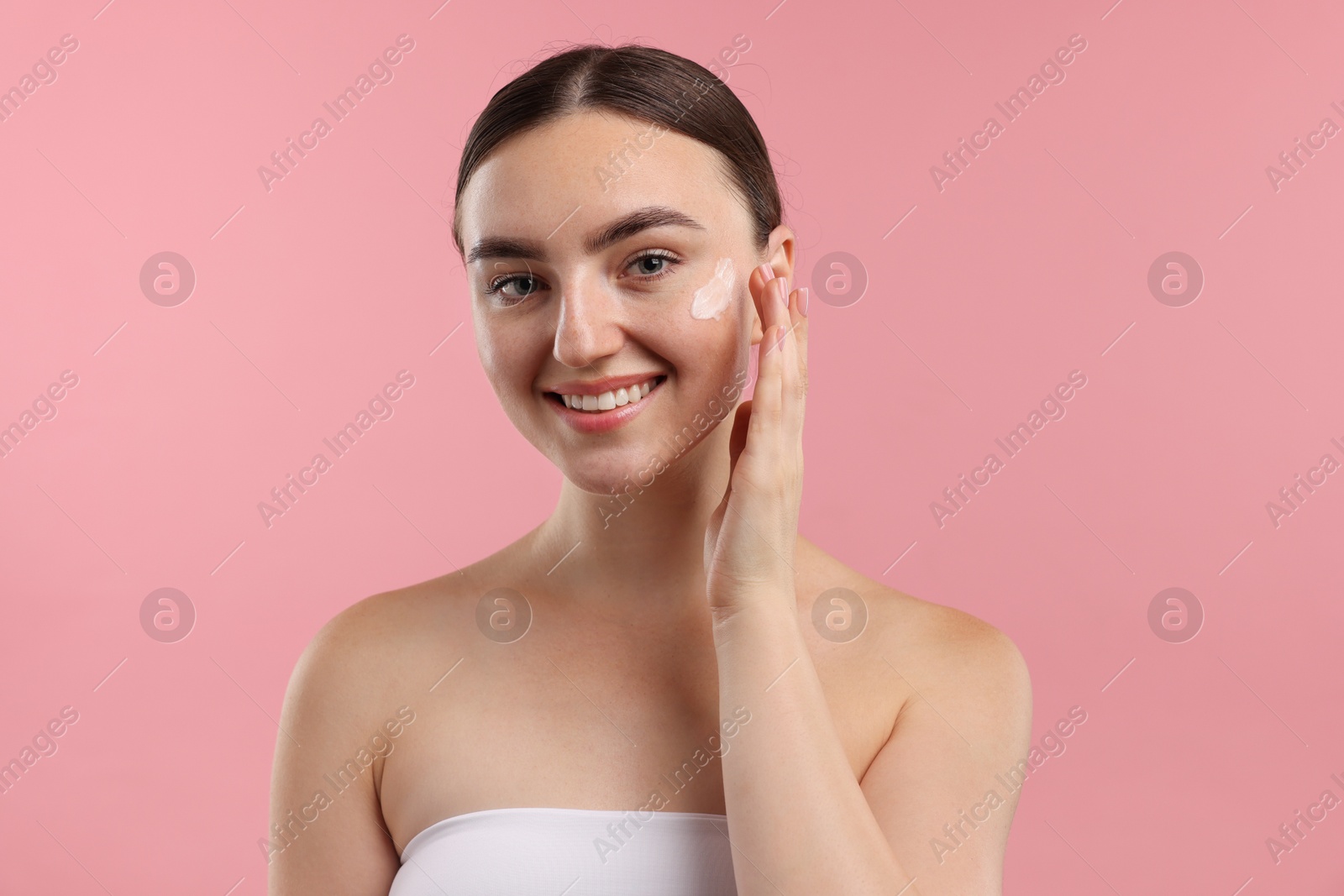 Photo of Beautiful woman with cream on her face against pink background