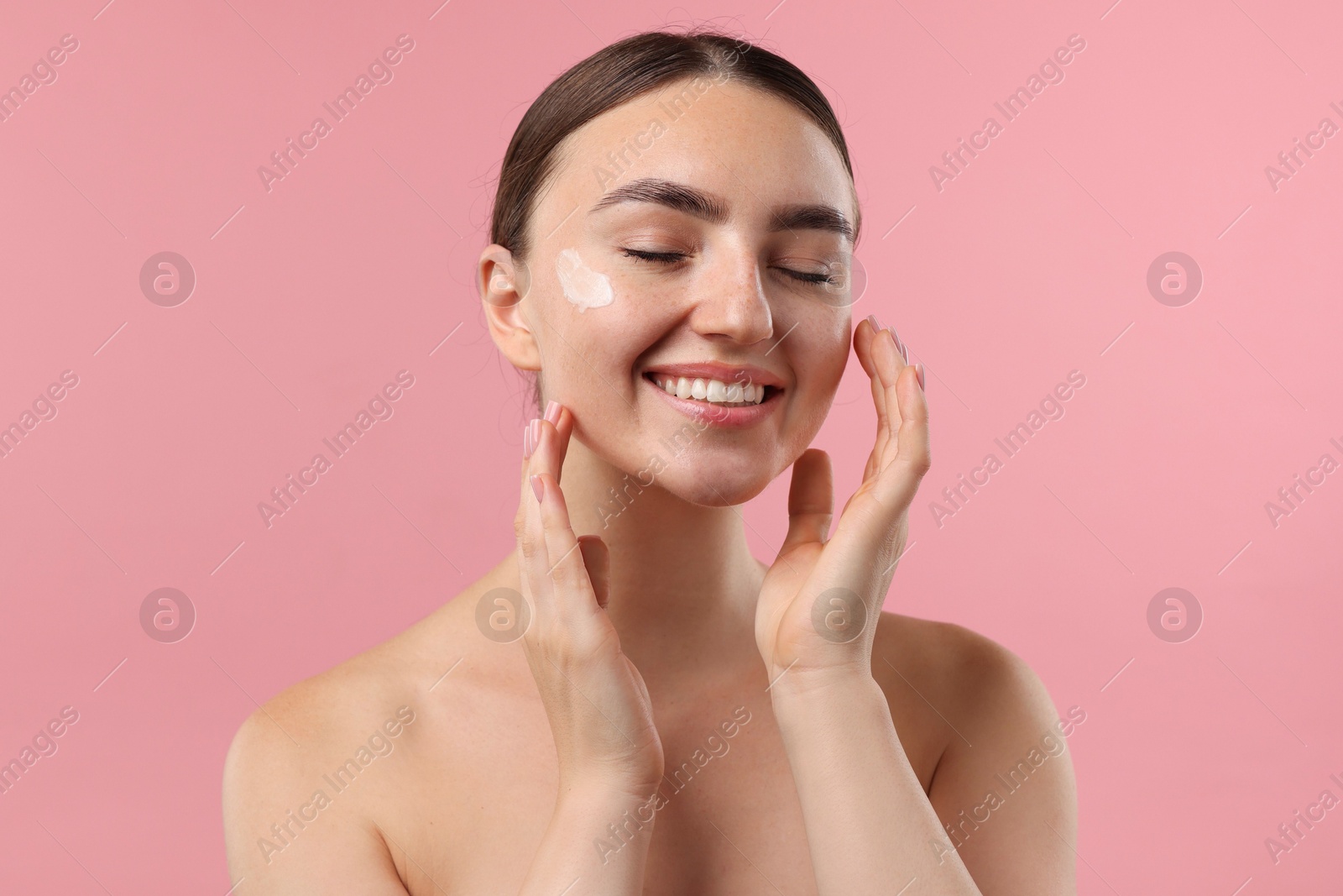 Photo of Beautiful woman with cream on her face against pink background