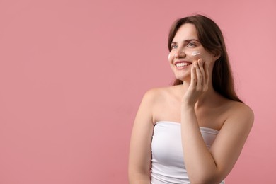 Photo of Beautiful woman with cream on her face against pink background. Space for text