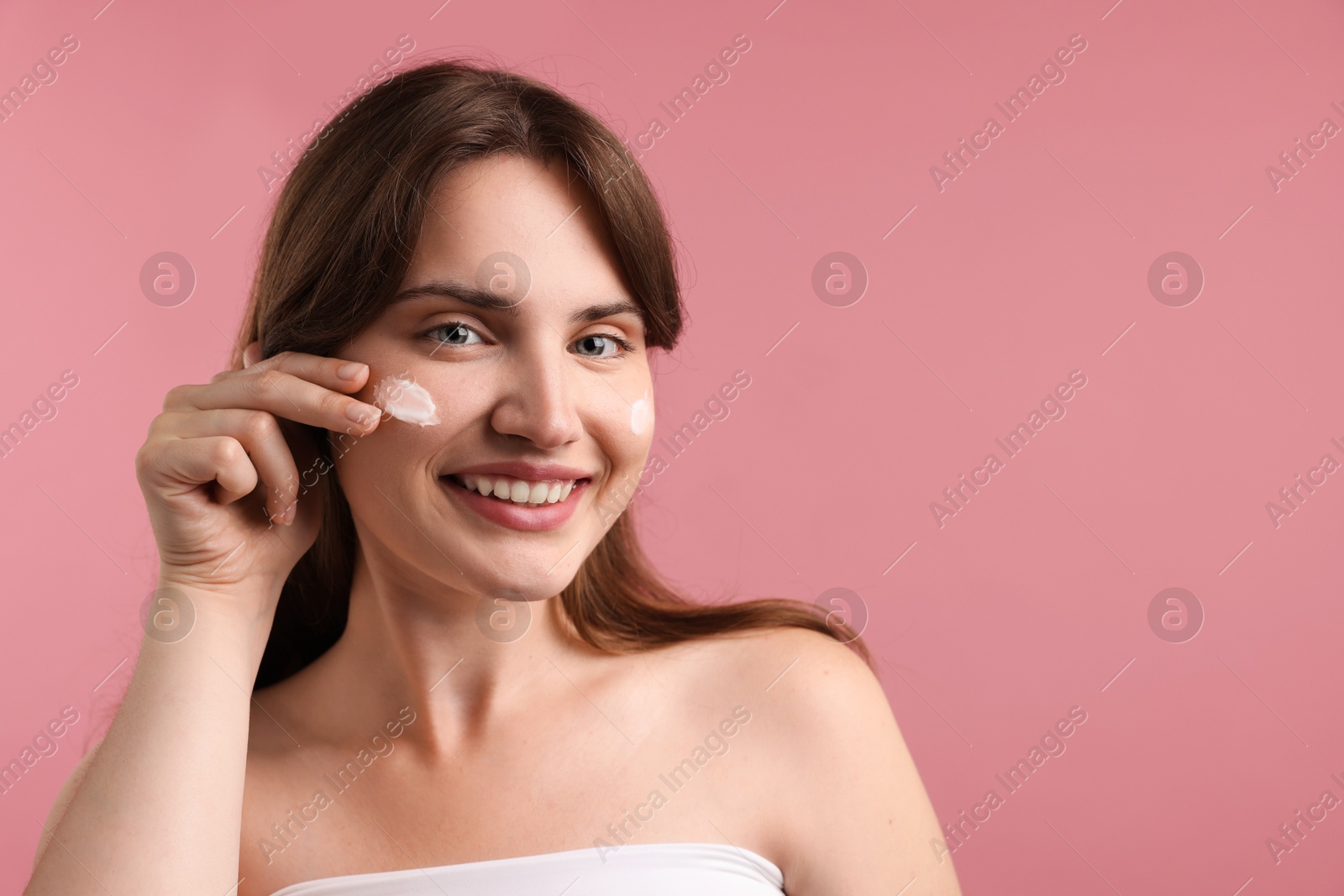 Beautiful woman with cream on her face against pink background. Space for text Photo of Beautiful woman with cream on her face against pink background. Space for text