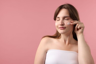 Photo of Beautiful woman with cream on her face against pink background. Space for text
