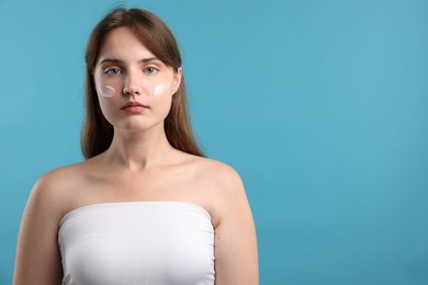 Photo of Beautiful woman with cream on her face against light blue background. Space for text