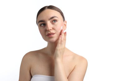 Photo of Beautiful woman applying cream onto her face on white background