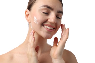 Photo of Beautiful woman applying cream onto her face on white background, closeup
