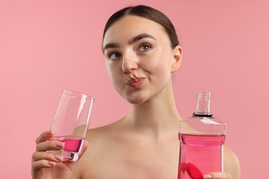 Photo of Woman rinsing mouth with mouthwash on pink background. Oral hygiene