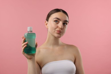 Photo of Woman rinsing mouth with mouthwash on pink background. Oral hygiene