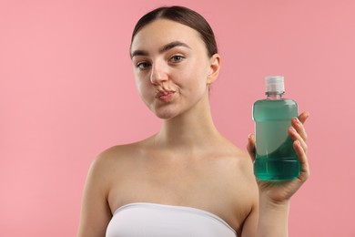 Photo of Woman rinsing mouth with mouthwash on pink background. Oral hygiene