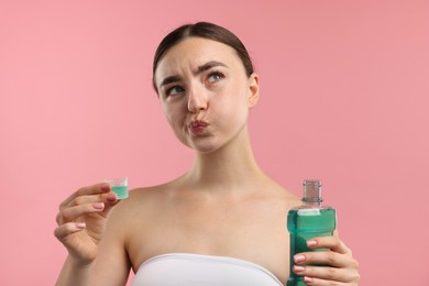 Photo of Woman rinsing mouth with mouthwash on pink background. Oral hygiene