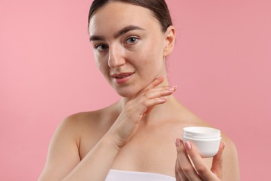 Photo of Beautiful woman with jar of face cream on pink background, closeup