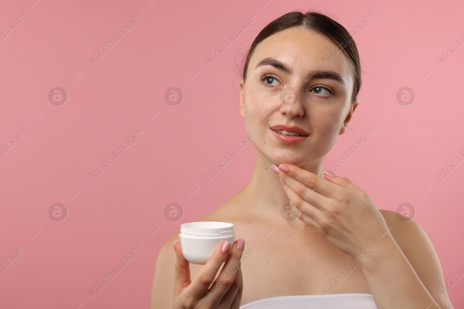 Photo of Beautiful woman with jar of face cream on pink background. Space for text