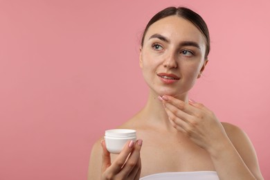 Photo of Beautiful woman with jar of face cream on pink background. Space for text
