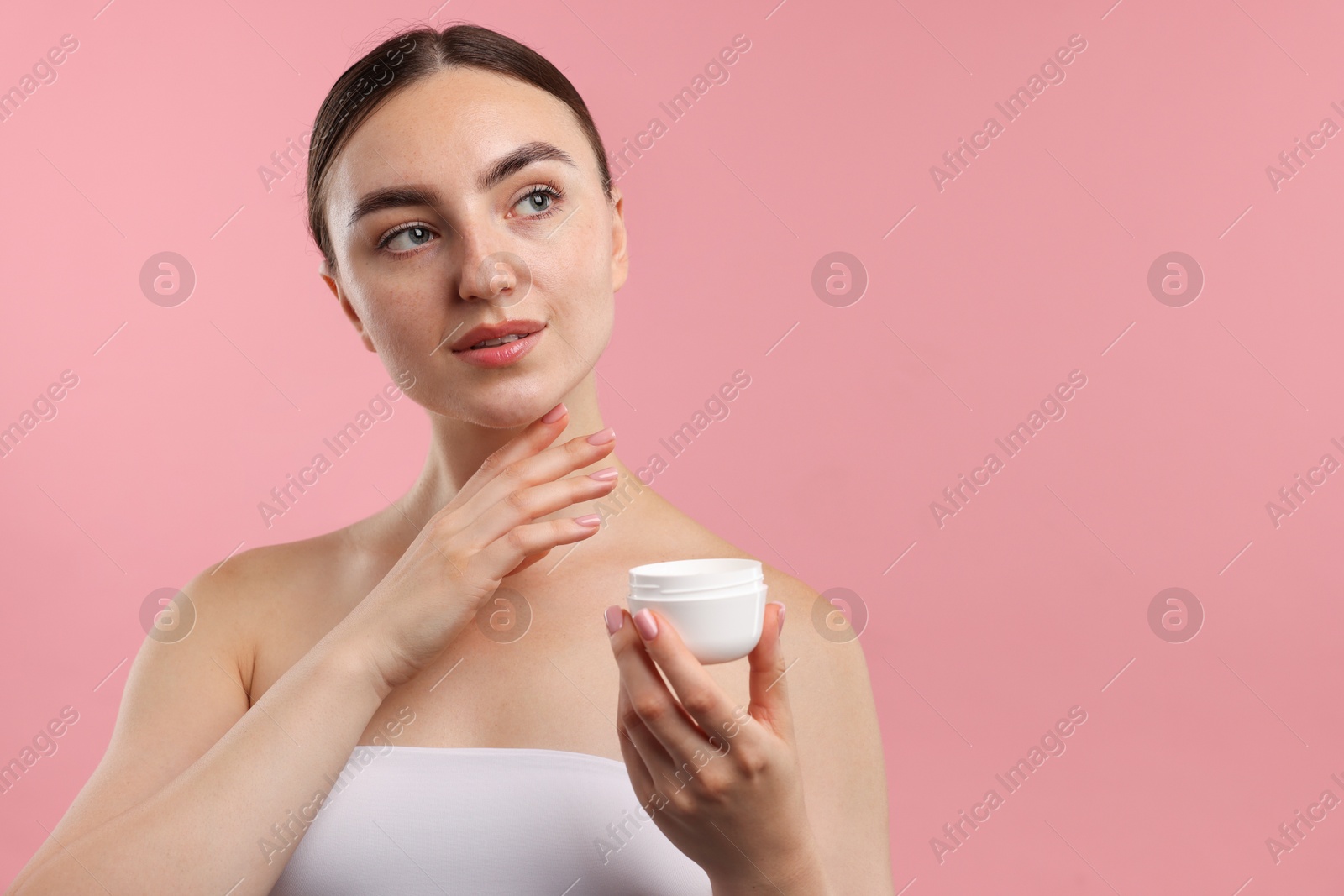 Photo of Beautiful woman with jar of face cream on pink background. Space for text