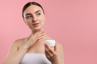 Photo of Beautiful woman with jar of face cream on pink background. Space for text