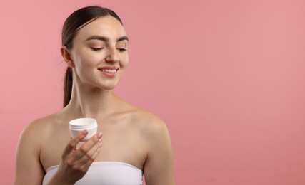 Photo of Beautiful woman with jar of face cream on pink background. Space for text
