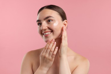Photo of Beautiful woman with cream on her face against pink background
