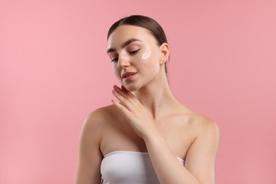 Photo of Beautiful woman with cream on her face against pink background